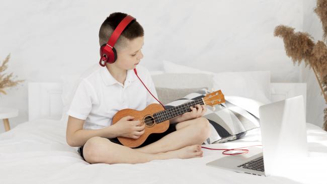 Niño tocando la guitarra conectado con sus auriculares