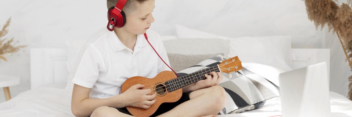 Niño tocando la guitarra conectado con sus auriculares